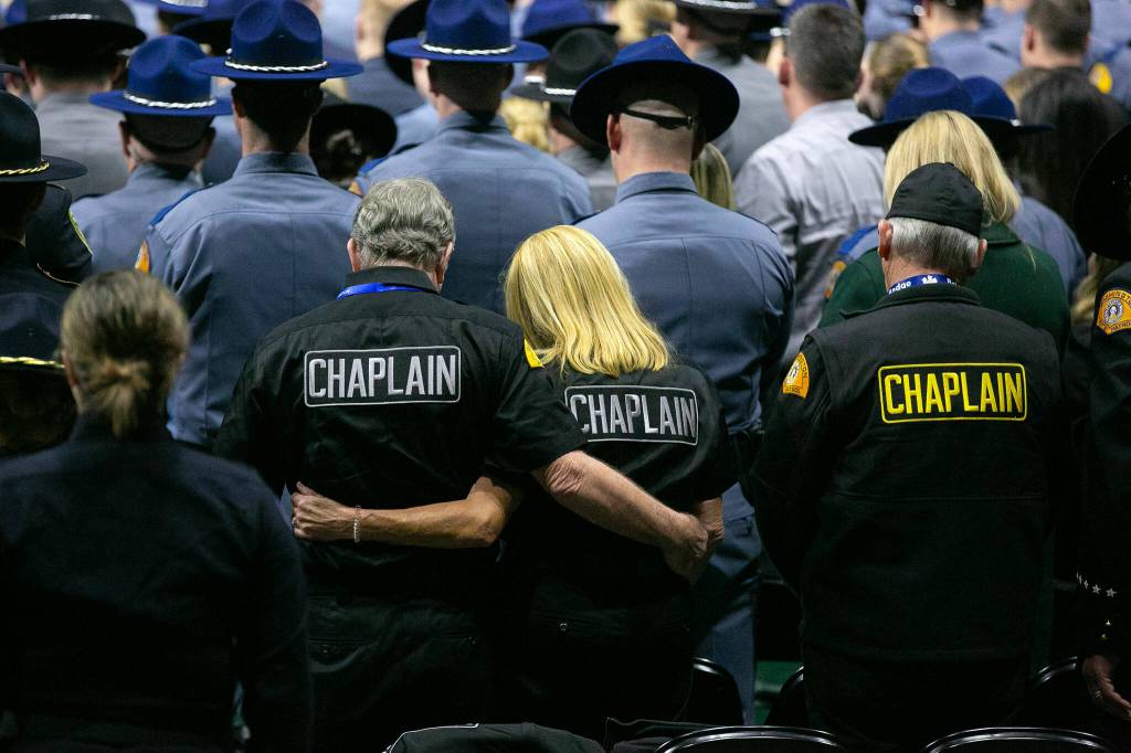 Chaplains listen as Taps is played during a memorial for Washington State Patrol trooper Chris Gadd on Tuesday, March 12, 2024, at Angel of the Winds Arena in Everett, Washington. (Ryan Berry / The Herald)