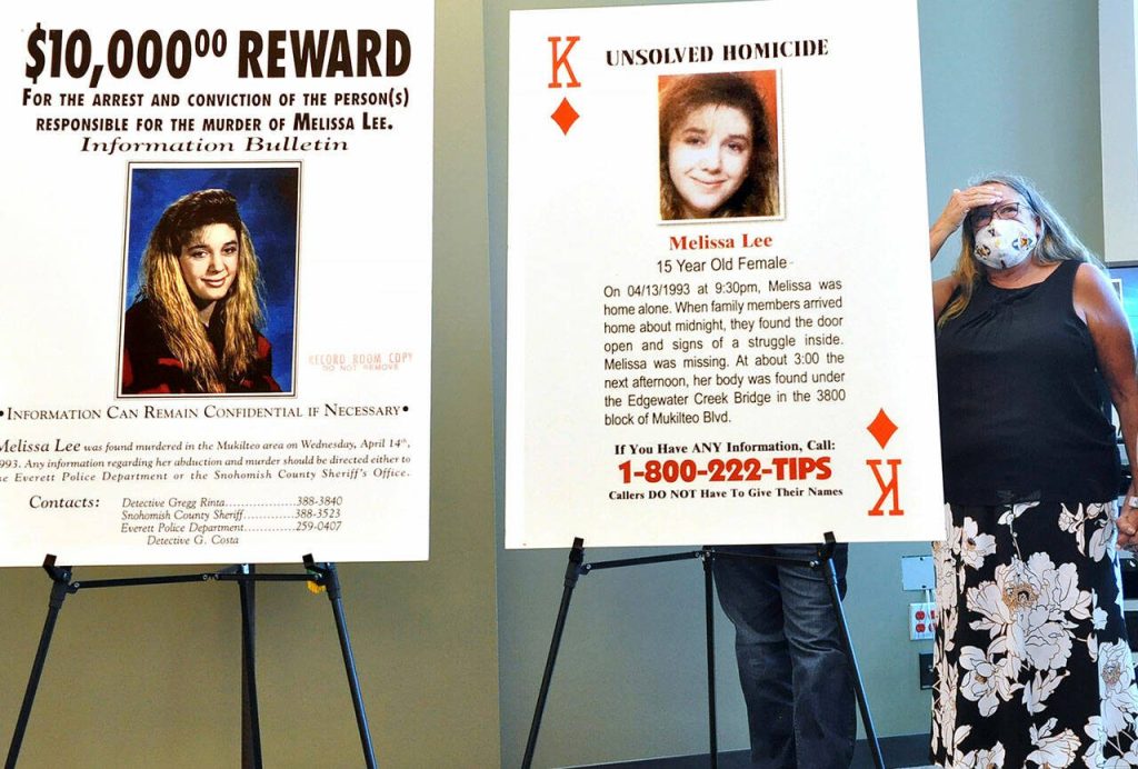 Sharon Lee (left), mother of Melissa Lee, stands by the posters of her daughter at an announcement that the Snohomish County Sheriffs Office had arrested a suspect in the 1993 cold case. (Sue Misao / The Herald)