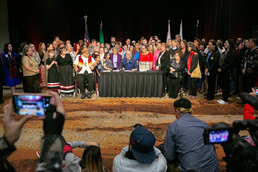Members of the Tulalip Nation gather behind Gov. Jay Inslee before Inslee signed into law HB 1879 on Tuesday, March 19, 2024, at Tulalip Casinoճ Orca Ballroom in Tulalip, Washington. (Ryan Berry / The Herald)