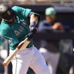 Seattle Mariners' Mitch Haniger hits a single against the San Diego Padres during the fourth inning of a spring training baseball game Monday, March 11, 2024, in Peoria, Ariz. (AP Photo/Lindsey Wasson)