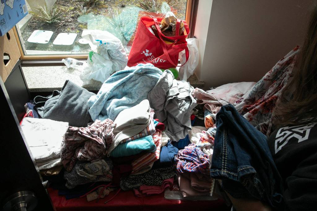 A woman picks through clothing during a resource fair at the Carnegie Resource Center on Wednesday, March 6, 2024, in downtown Everett, Washington. (Ryan Berry / The Herald)