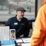 Jason Hauff, community engagement manager with United Healthcare, speaks with people about Medicaid options during a resource fair at the Carnegie Resource Center on Wednesday, March 6, 2024, in downtown Everett, Washington. (Ryan Berry / The Herald)