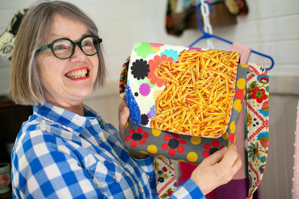 Artist Frances Peterson cracks a smile while showing off a bag of her design at Milkwood on Sunday, March 31, 2024, in Index, Washington. (Ryan Berry / The Herald)