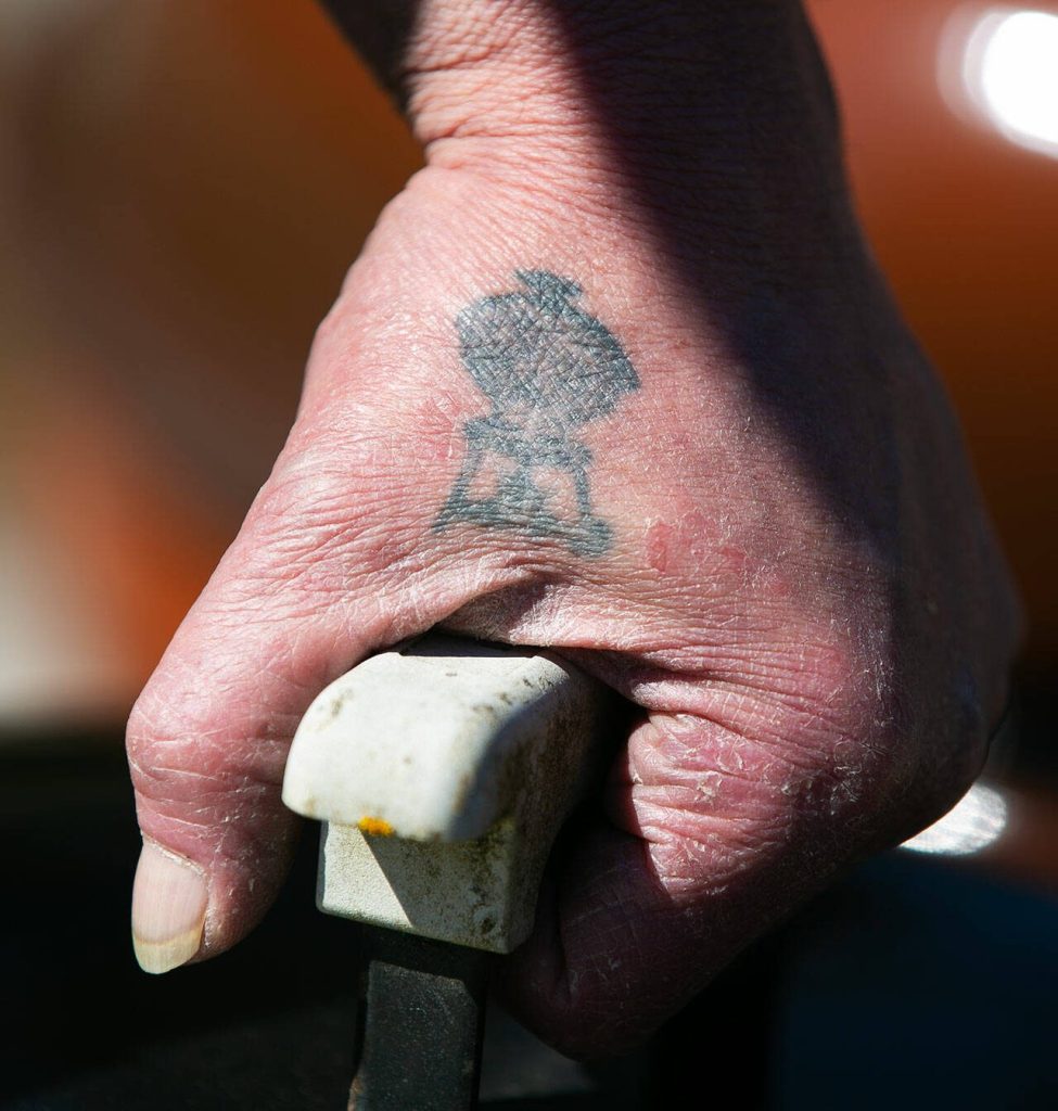 Jimmer De Groots Weber grill tattoo catches the sun as he grabs the lid of one of his two-dozen grills. (Ryan Berry / The Herald)