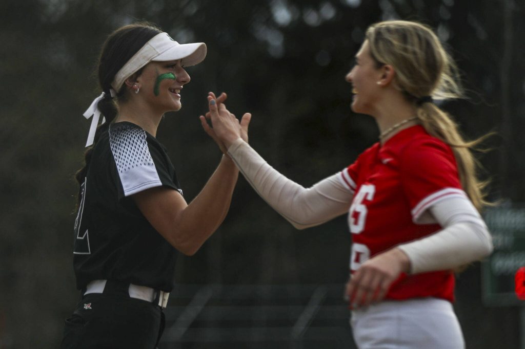 Jacksons Allie Thomsen (22) high-fives a Stanwood player during a prep softball game between Stanwood and Jackson at Henry M. Jackson High School on Tuesday, April 2, 2024 in Mill Creek, Washington. Jackson won, 6-0. (Annie Barker / The Herald)
