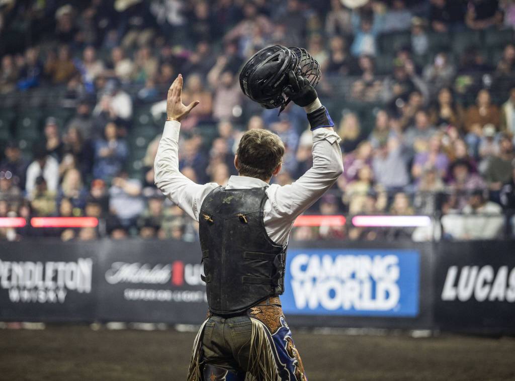 Cort McFadden raises his arms in celebration during PBR Everett at Angel of the Winds Arena on Wednesday, April 17, 2024 in Everett, Washington. (Olivia Vanni / The Herald)