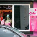 Emma Dilemma, a makeup artist and bikini barista for the last year and a half, serves a drink to a customer while dressed as Lily Munster Tuesday, Oct. 25, 2022, at XO Espresso on 41st Street in Everett, Washington. (Ryan Berry / The Herald)