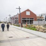 People walk along the waterfront in front of South Fork Bakery at the Port of Everett on Thursday, April 11, 2024 in Everett, Washington. (Olivia Vanni / The Herald)