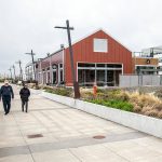 People walk along the waterfront in front of South Fork Bakery at the Port of Everett on Thursday, April 11, 2024 in Everett, Washington. (Olivia Vanni / The Herald)