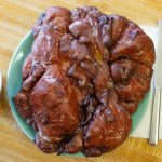 A giant seven-dollar apple fritter eclipses a plate on Wednesday, April 17, 2024, at Karl’s Bakery in Everett, Washington. (Ryan Berry / The Herald)