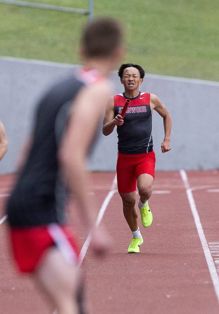 Stanwoods leadoff runner in the boys 1,600-meter relay grimaces while running toward his teammate during the Eason Invitational at Snohomish High School on Saturday, April 20, 2024 in Snohomish, Washington. (Olivia Vanni / The Herald)