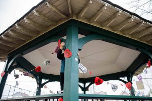 People hang up hearts with messages about saving the Clark Park gazebo during a “heart bomb” event hosted by Historic Everett on Saturday, Feb. 17, 2024 in Everett, Washington. (Olivia Vanni / The Herald)
