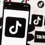 FILE - The TikTok logo is displayed on a mobile phone in front of a computer screen, Oct. 14, 2022, in Boston. TikTok is gearing up for a legal fight against a U.S. law that would force the social media platform to break ties with its China-based parent company or face a ban. A battle in the courts will almost certainly be backed by Chinese authorities as the bitter U.S.-China rivalry threatens the future of a wildly popular way for young Americans to connect online.  (AP Photo/Michael Dwyer, File)