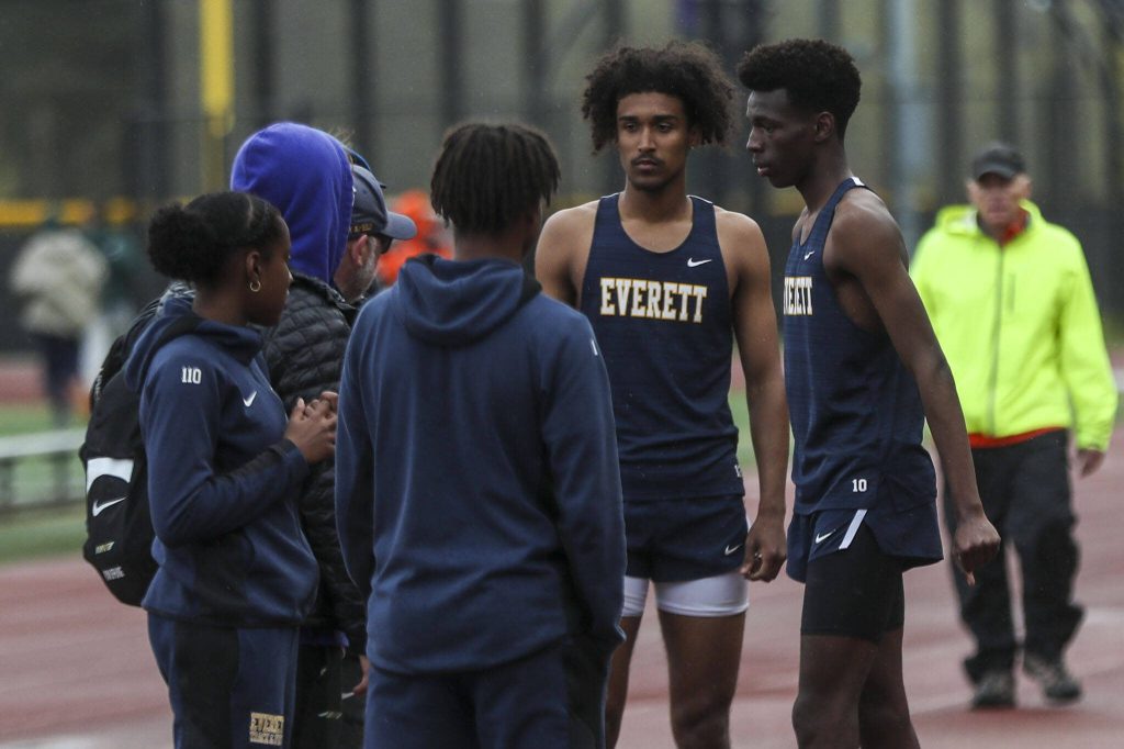 Everetts Shukurani Ndayiragije, right, talks with friends after participating in the triple jump event during a track meet between Lynnwood, Everett, and Edmonds-Woodway at Edmonds District Stadium on Thursday, April 25, 2024 in Edmonds, Washington. (Annie Barker / The Herald)