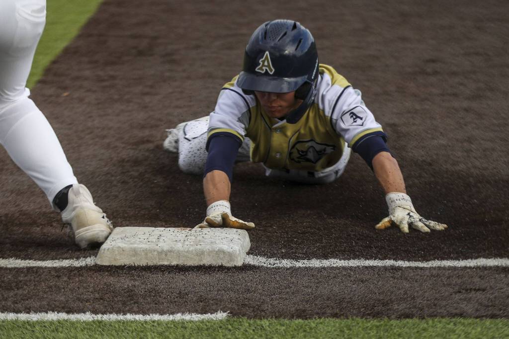 An Arlington player slides into first during a baseball game between Monroe and Arlington at Monroe High School on Friday, April 26, 2024 in Monroe, Washington. Monroe secured a win in an eighth inning, 4-3. (Annie Barker / The Herald)