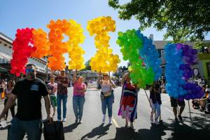 People begin parading down First Street with a giant balloon “PRIDE” during Snohomish’s inaugural Pride celebration on Saturday, June 3, 2023, in downtown Snohomish, Washington. (Ryan Berry / The Herald)