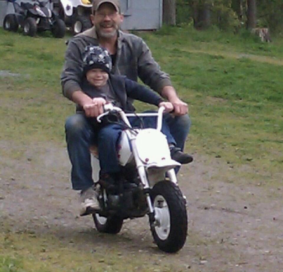 John Wightman rides a motorbike with his grandson Jaxon at his property in Marysville, Washington in 2011. (Photo provided by Kristen Velez)