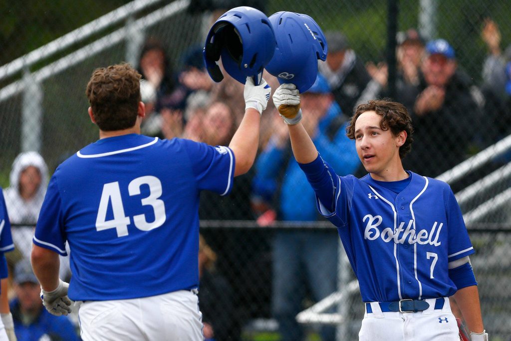 Bothells Nolan Ledoux, left, bumps helmets with teammate Brady Stutz after knocking one out of the park during a playoff baseball game against Lake Stevens on Saturday, May 4, 2024, in Lake Stevens, Washington. (Ryan Berry / The Herald)