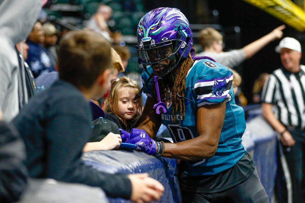 Wideout Vincent Wilkerson signs a hat for a young fan before taking a kick return during the Washington Wolfpacks inaugural home opener against Billings on Sunday, May 5, 2024, a Angel of the Winds Arena in Everett, Washington. (Ryan Berry / The Herald)