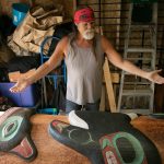 Tlingit Artist Fred Fulmer stands over a completed information totem pole inside his workshop on Wednesday, May 8, 2024, at his home in Everett, Washington. The pole will be packed up in the coming days and shipped to Petersburg, Alaska. (Ryan Berry / The Herald)