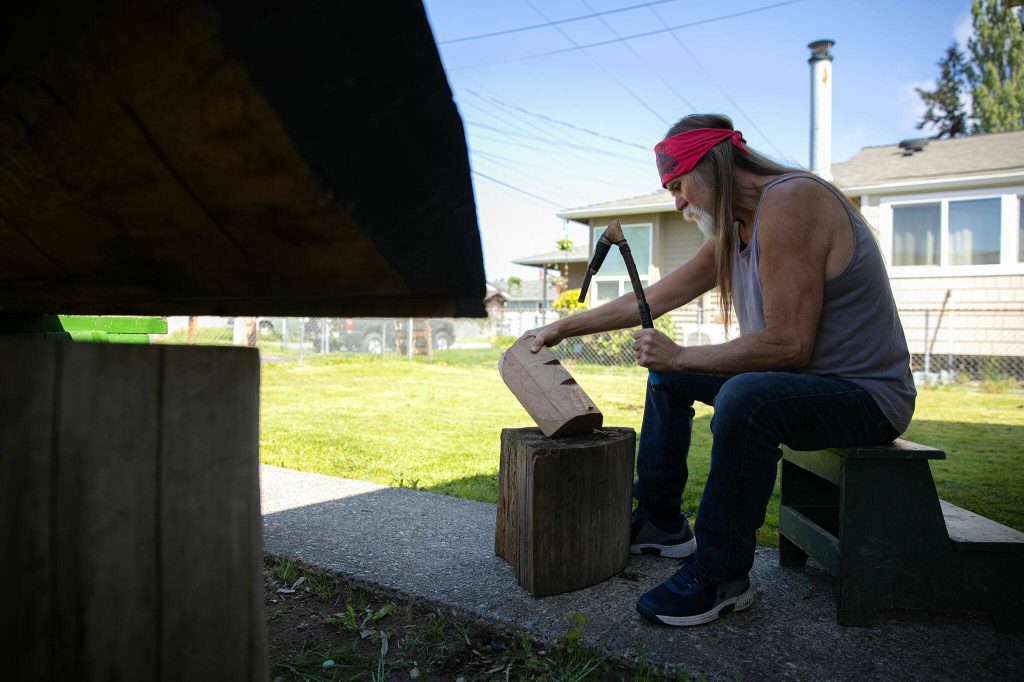 Tlingit Artist Fred Fulmer works on a wooden mask with an adze to demonstrate his carving technique on Wednesday, May 8, 2024, at his home in Everett, Washington. (Ryan Berry / The Herald)