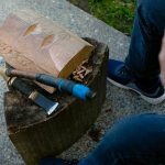 Tlingit Artist Fred Fulmer works on a wooden mask with an adze to demonstrate his carving technique on Wednesday, May 8, 2024, at his home in Everett, Washington. (Ryan Berry / The Herald)