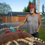 Tlingit Artist Fred Fulmer stands by one of his completed totem poles on Wednesday, May 8, 2024, at his home in Everett, Washington. This pole is not the one being sent to Alaska. (Ryan Berry / The Herald)