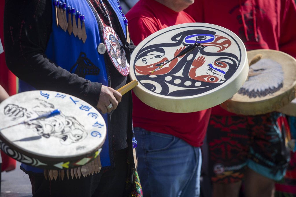 People drum during a blessing song during a ceremony for the healing pole students spent the last year carving along with Tulalip carver James Madison at Archbishop Murphy High School in Everett, Washington on Wednesday, May 15, 2024. (Annie Barker / The Herald)