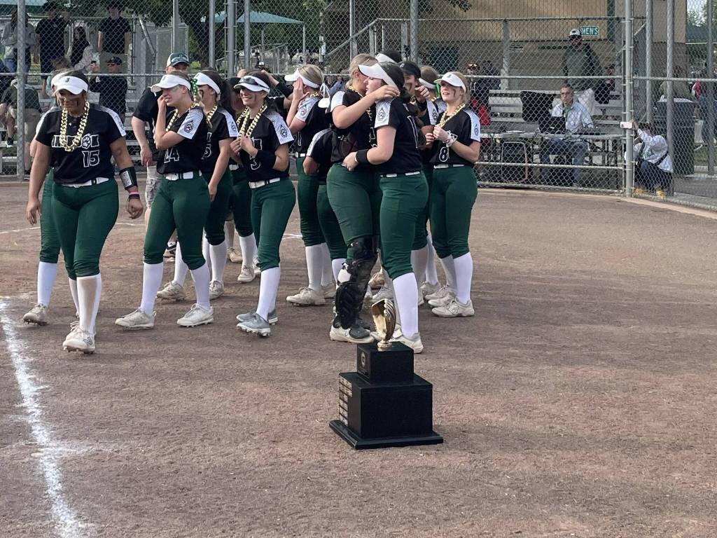 The Jackson softball team alternates between laughing and crying next to the Class 4A state tournament trophy after a 10-1 triumph over Emerald Ridge Saturday, May 25 at Columbia Playfield in Richland, WA. (Aaron Coe / The Herald).