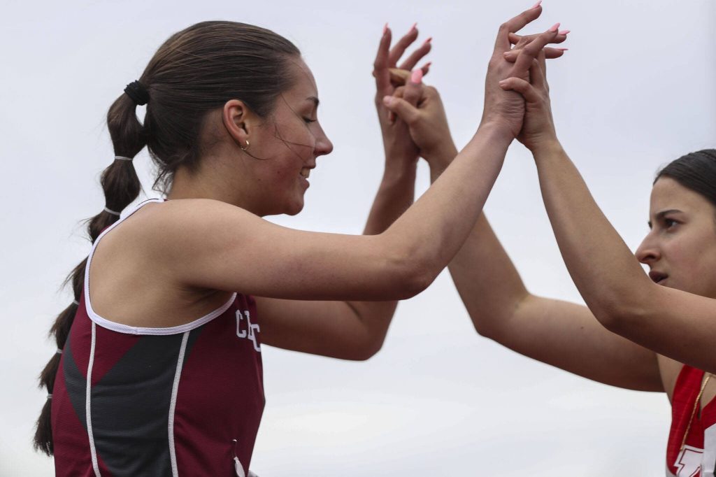 Cedarcrests Laine McKenzie high-fives another runner after the Girls 200M 2A dash during the Class 4A, 3A, 2A track and field state championships at Mount Tahoma High School in Tacoma, Washington on Saturday, May 25, 2024. (Annie Barker / The Herald)