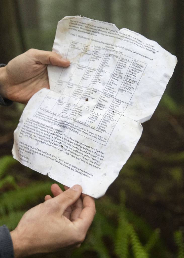 Greg Morrow holds a sheet showing different guidelines used to determine deep-seated landslide activity levels on Wednesday, May 29, 2024 in Arlington, Washington. (Olivia Vanni / The Herald)