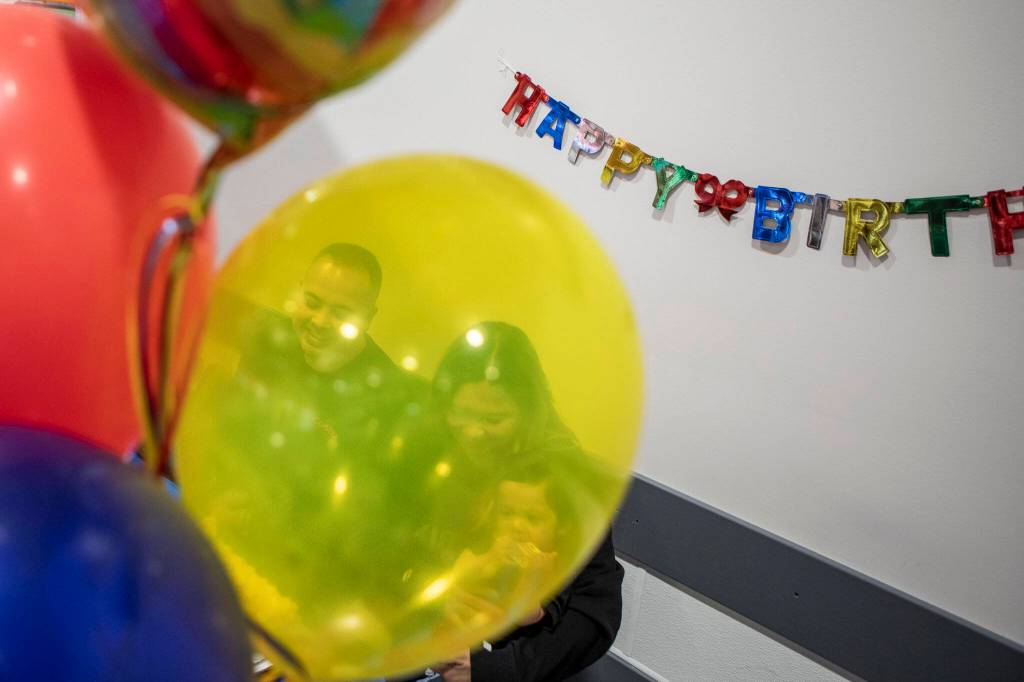 Left to right, Angelo Sarmiento, Jona Sarmiento and Carlisle Sarmiento prepare to cut the cake during a first birthday party at Costco in Lake Stevens on Friday, May 31, 2024. (Annie Barker / The Herald)
