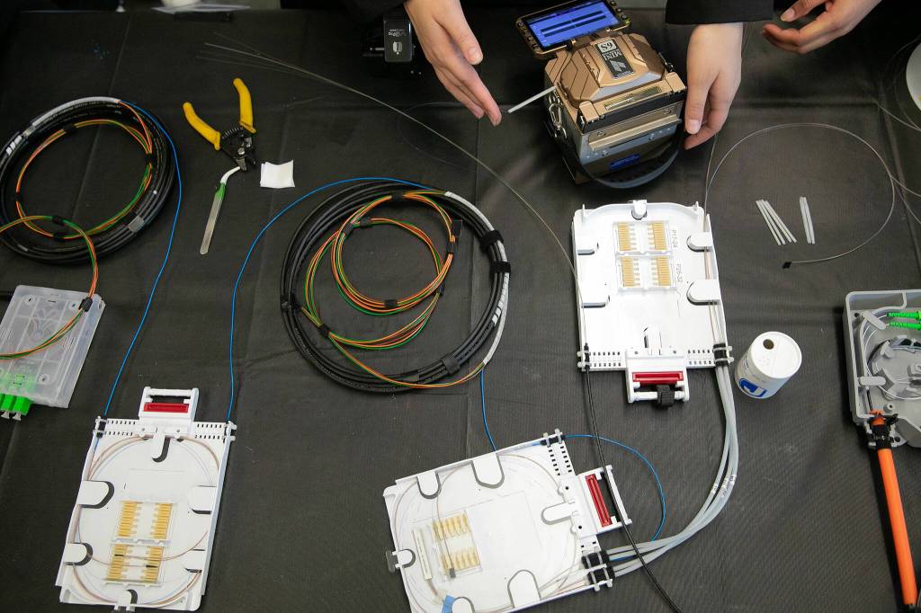Students work with materials laid out on a table during a fiber optic technician training demonstration at Sno-Isle TECH Skills Center on Tuesday, May 28, 2024, in Everett, Washington. (Ryan Berry / The Herald)