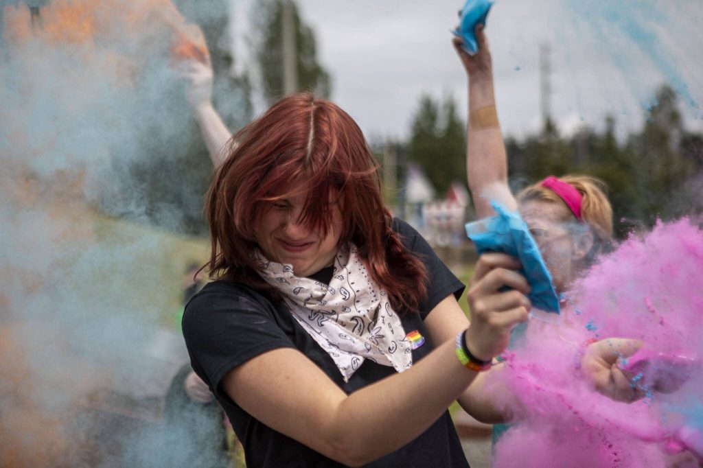 People participate in the color throw event involving colorful packets of corn starch during the Stanwood-Camano Pride event at Freedom Park in Camano, Washington on Saturday, June 1, 2024. (Annie Barker / The Herald)