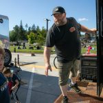Jason Bauer, of Warpig Smokehouse, steps outside his food truck to deliver an order at the Lake Stevens Farmers Market on Wednesday, June 12, 2024, in Lake Stevens, Washington. (Ryan Berry / The Herald)