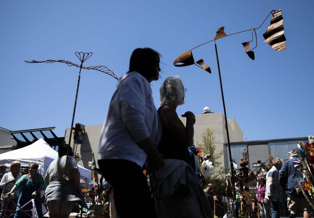 People pause to look at a salmon metal work during Sorticulture on Friday, June 7, 2024, in Everett, Washington. (Olivia Vanni / The Herald)