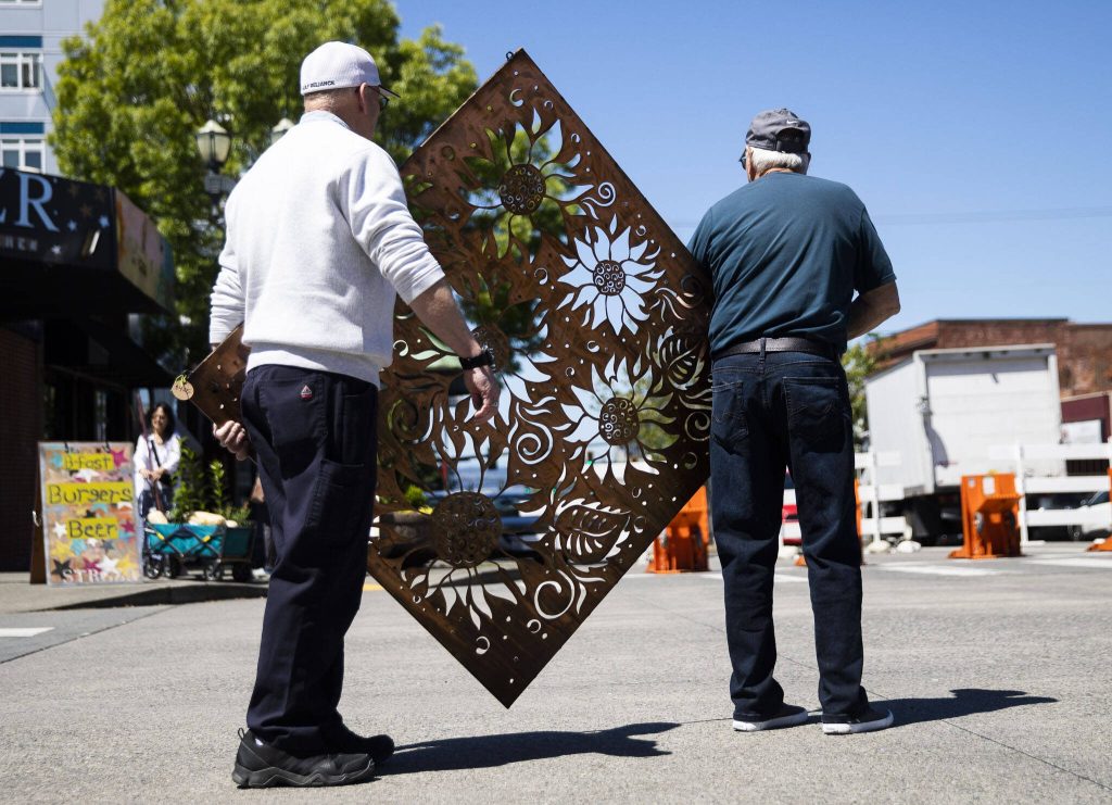 Two men carry a large metal work through Sorticulture on Friday, June 7, 2024, in Everett, Washington. (Olivia Vanni / The Herald)