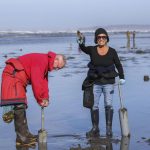 Providenza Simpson celebrates catching a mossback – a large razor clam – on Mocrocks Beach in Moclips, Washington, shortly after low tide on March 14 while Joe Simpson uses a clam gun to dig for another one. The Simpsons came from Tacoma, a drive they have made many times before during razor clam season. (Brenda Mann Harrison / Special to The Herald)