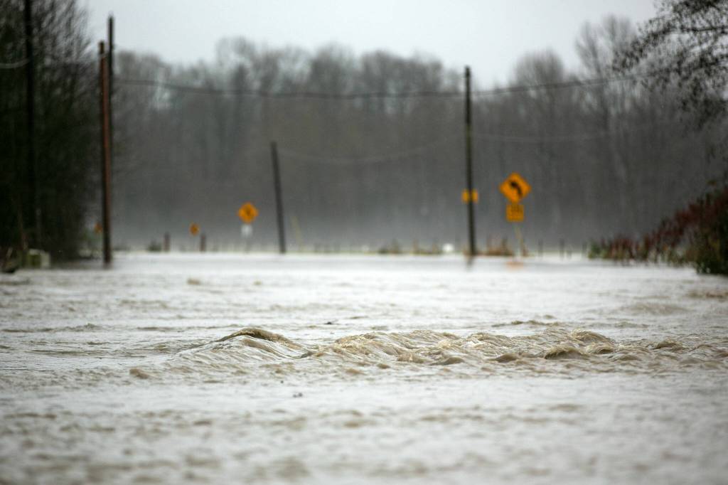 Water from the Stillaguamish rapidly flows over Pioneer Highway during heavy flooding on Tuesday, Dec. 5, 2023, just north of Silvana, Washington. (Ryan Berry / The Herald)