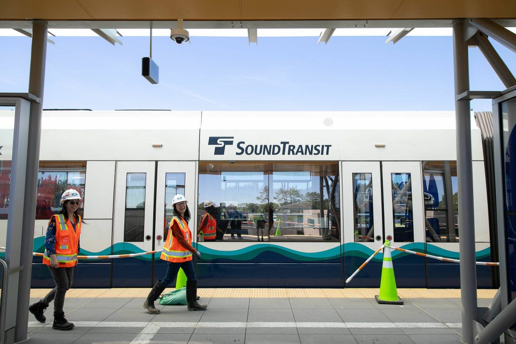 Two workers walk past a train following a press event at the Lynnwood City Center Link Station on Friday, June 7, 2024, in Lynnwood, Washington. (Ryan Berry / The Herald)