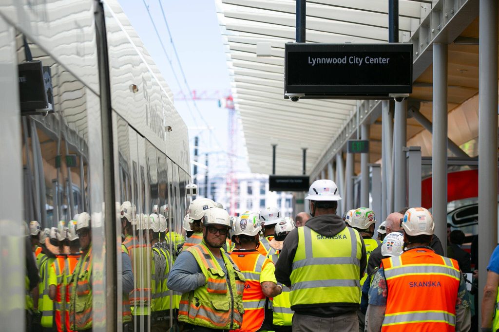 Construction crew members stand together while attending a press event at the Lynnwood City Center Link Station on Friday, June 7, 2024, in Lynnwood, Washington. (Ryan Berry / The Herald)