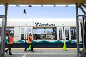 Two workers walk past a train following a press event at the Lynnwood City Center Link Station on Friday, June 7, 2024, in Lynnwood, Washington. (Ryan Berry / The Herald)