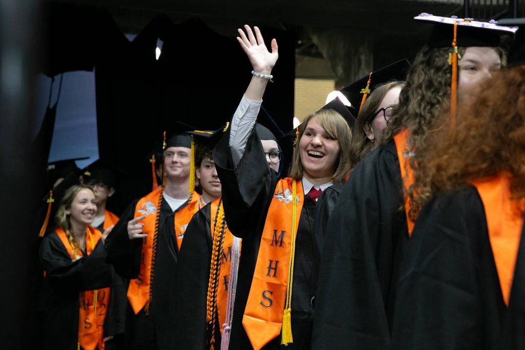 Students wait in the wings and wave to family before the processional during Monroe High Schools 2024 commencement on Wednesday, June 12, 2024, at Angel of the Winds Arena in Everett, Washington. (Ryan Berry / The Herald)