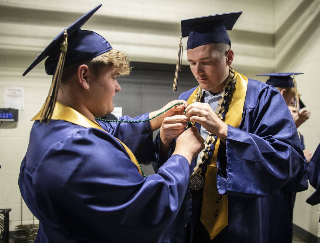 Parker Kinney, left, and Camden Matter try to fix a loose honor cord before walking at Arlington High School graduation at Angel of the Winds Arena on Thursday, June 13, 2024, in Everett, Washington. (Olivia Vanni / The Herald)