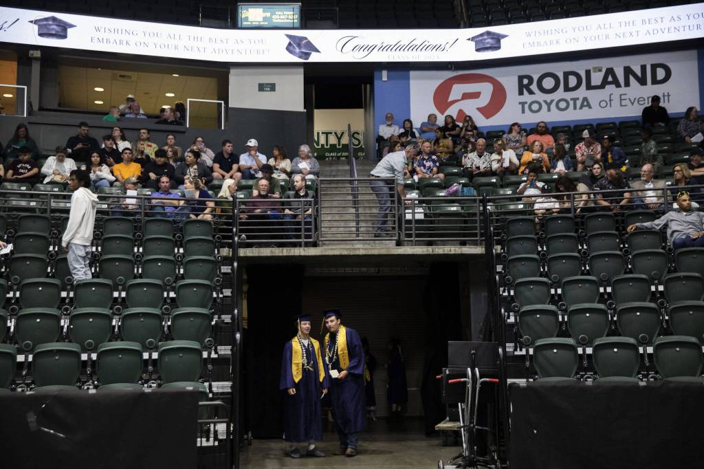 Kobi Spady, left, and Willem Van Dongen look out as people file in before the start of Arlington High School graduation at Angel of the Winds Arena on Thursday, June 13, 2024, in Everett, Washington. (Olivia Vanni / The Herald)