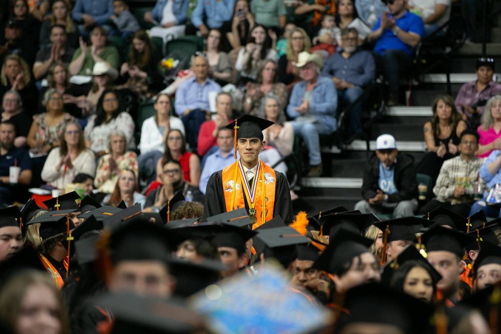 Roger Rojas, a valedictorian for the Monroe High School class of 2024, stands to be recognized during commencement on Wednesday, June 12, 2024, at Angel of the Winds Arena in Everett, Washington. (Ryan Berry / The Herald)