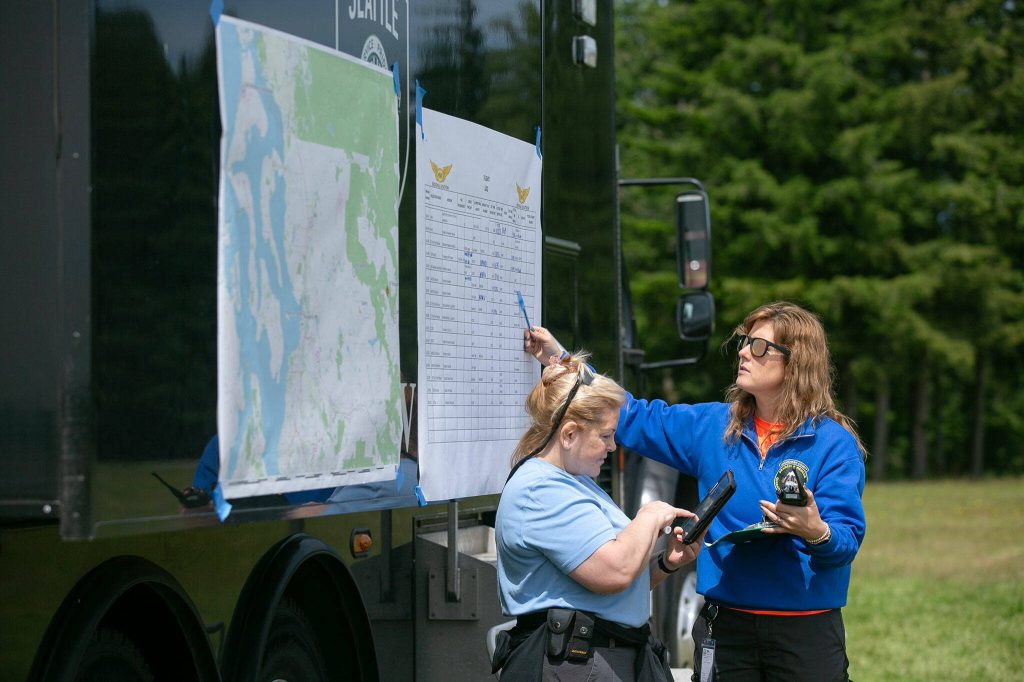 Emergency workers keep track of flight departure and arrival times at home base during an interagency training session held by Northwest Regional Aviation on Thursday, June 13, 2024, at the Arlington Airport in Arlington, Washington. (Ryan Berry / The Herald)