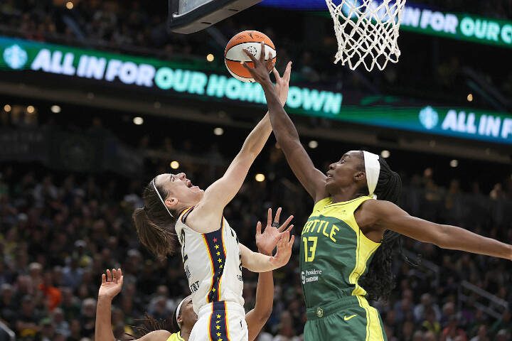 Caitlin Clark (22) of the Indiana Fever has her shot blocked by Ezi Magbegor (13) of the Seattle Storm on May 22 in Seattle. (Steph Chambers / Getty Images, file)