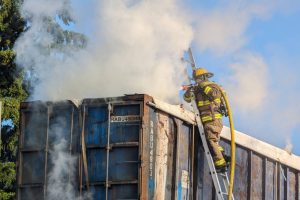 A Marysville firefighter sprays water on a smoking rail car at the intersection of 116th Street NE and State Avenue around 8 a.m. Thursday, June 13, 2024, in Marysville, Washington. (Mike Henneke / The Herald)