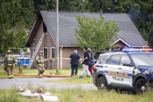 Firefighters and police walk around a home on Ed Williams Road that caught fire on Tuesday, June 18, 2024 in Tulalip, Washington. (Olivia Vanni / The Herald)